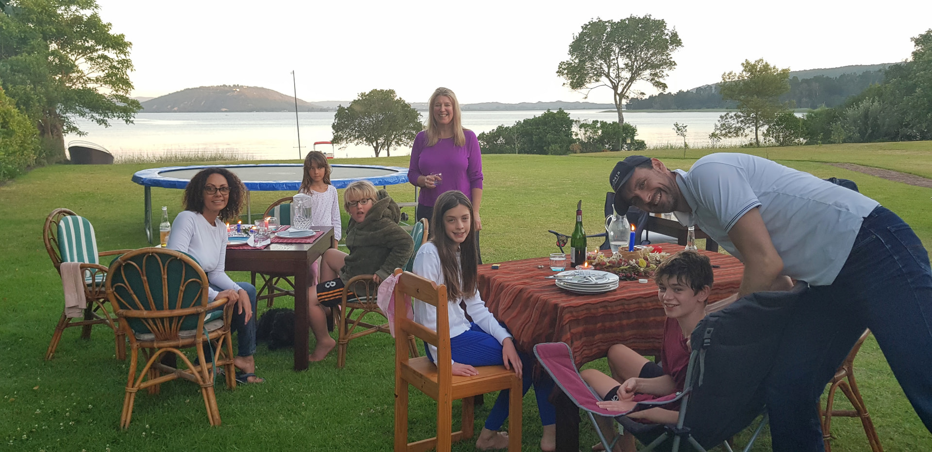 Family enjoying an evening meal on the lawn beside the lake