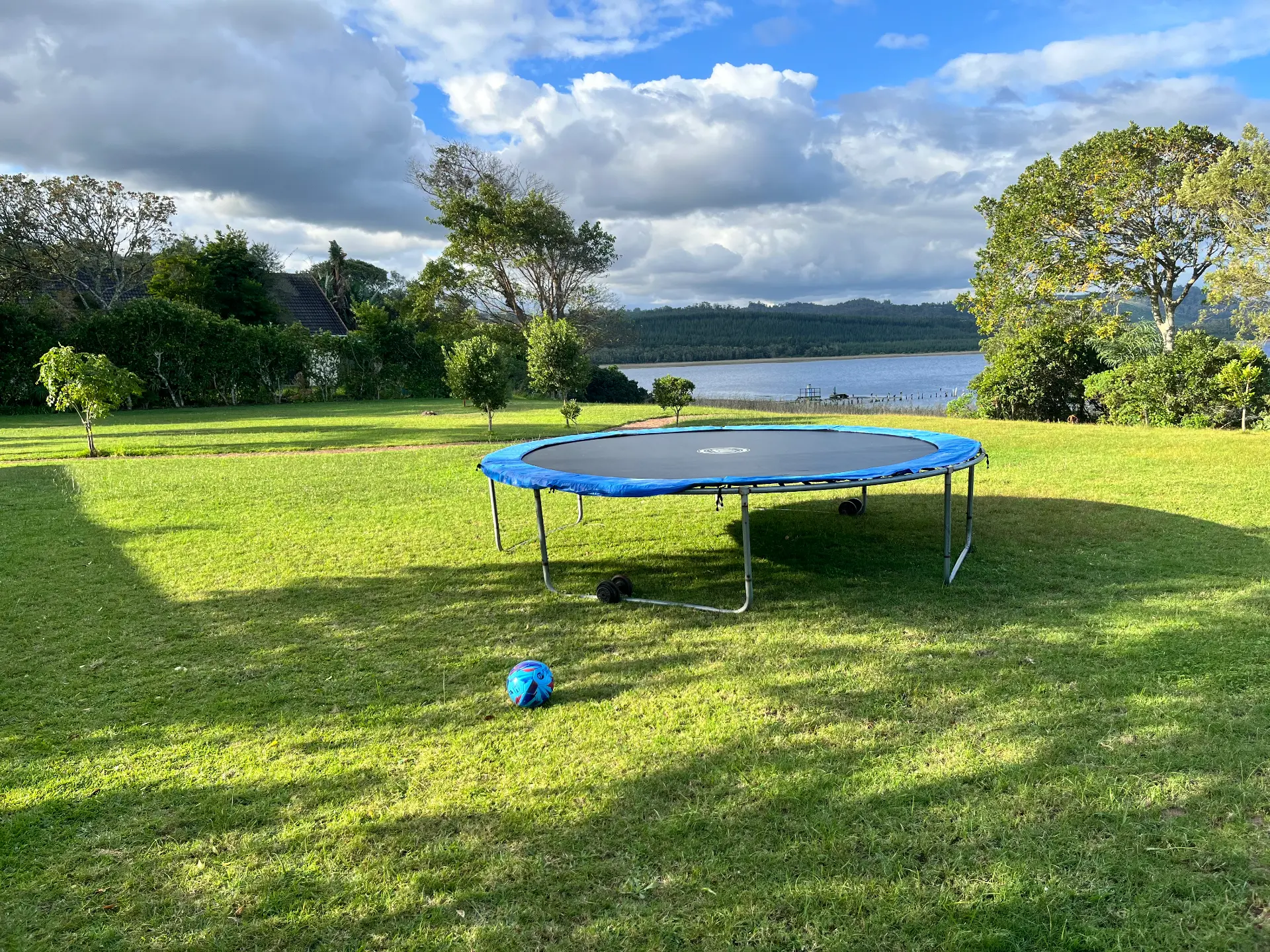 Trampoline and ball on the estate lawn overlooking the lake