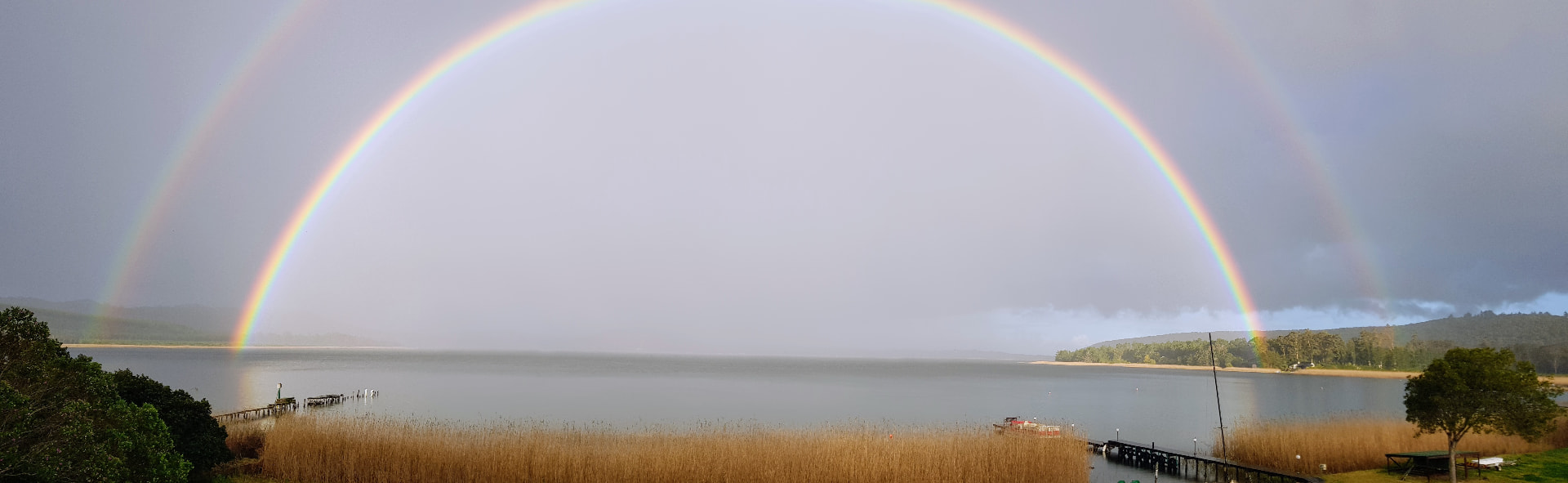 Double rainbow arching over Swartvlei Lake and the estate jetty